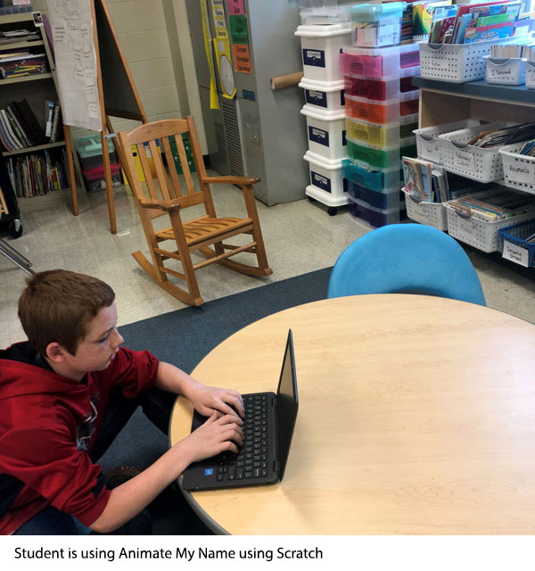 A student is sitting in front of a computer typing. He is using 'Animate My Name' using scratch.