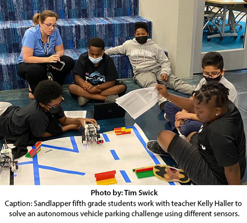 5 Sandlapper fifth grade students work with teacher Keylly Haller to solve an autonomous vehicle parking challenge using different sensors.
