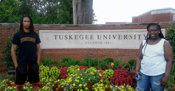 Image shows two people standing next to the plaque for Tuskegee University